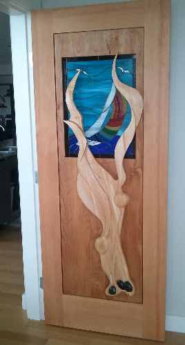 Carved Door with kelp flowing over stain glassed sail boat window